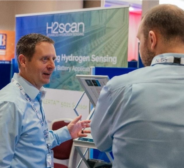 H2scan's Jeff Donato speaks with a conference participant at the H2scan booth during the NIBS 2023 Battery Conference.
